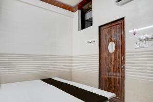 a small room with a bed and a wooden door at SPOT ON Radhakund Guest House in Rādha Kund +21 photos