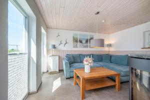 a living room with a blue couch and a table at Huus Strandgut in Fehmarn