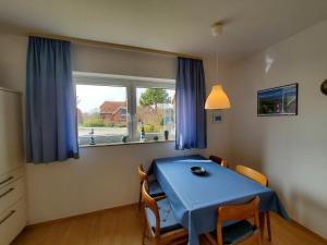 une table bleue et des chaises dans une chambre avec fenêtre dans l'établissement Sundby, à Lemkenhafen auf Fehmarn
