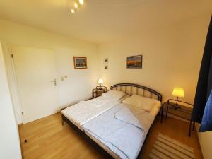 - une chambre avec un lit et deux lampes sur deux tables dans l'établissement Sundby, à Lemkenhafen auf Fehmarn