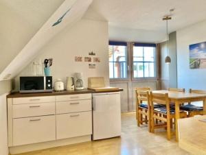 a kitchen and dining room with white cabinets and a table at Kajüte 4 in Lemkenhafen auf Fehmarn