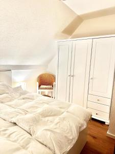 a bedroom with a large white bed and a chair at Havnkoje in Lemkenhafen auf Fehmarn