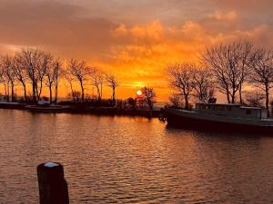 a boat on the water with a sunset in the background at Havnkoje in Lemkenhafen auf Fehmarn