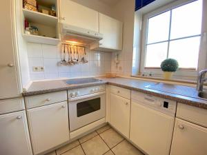 a kitchen with white cabinets and a sink and a window at Orth A3 - Hafentraum in Orth +3 photos