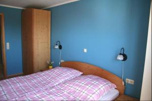 a bedroom with a bed with a blue wall and two lamps at Orther Hafenblick in Orth