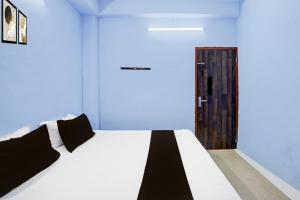 a bedroom with a white bed and a wooden door at HOTEL O PRAGYA 6 in Raipur +21 photos
