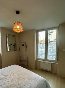 a bedroom with a bed and a lamp and two windows at Centre ville - Berthelot in Chamalières
