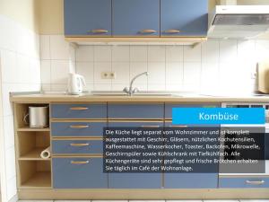a kitchen with blue cabinets and a sign that says korman at Hafenblick in Orth