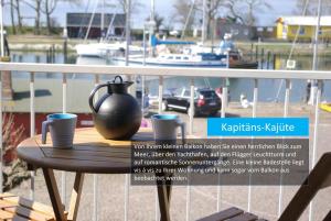a table with cups and a vase on a balcony at Hafenblick in Orth