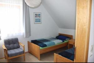 a small bedroom with a bed and a chair at Lichtblick in Petersdorf auf Fehmarn