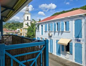 a white building with blue windows and a clock tower at La Maison Jaune - Swimming pool & beach access 50 m away in Saint-Pierre