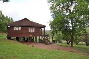 a large wooden house with a staircase next to a tree at Gunyatoo Trout Trout Farm & Guest Lodge in Sabie