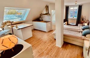 a bedroom with a bed and a desk and a kitchen at meerHAFEN in Orth +6 photos