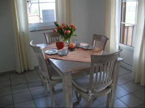 a wooden table with chairs and a vase of flowers on it at Wohnung mit Balkon und Aussicht in Petersdorf auf Fehmarn
