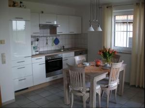 a kitchen with a table and chairs and a kitchen with white cabinets at Wohnung mit Balkon und Aussicht in Petersdorf auf Fehmarn