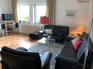 un salon avec un canapé noir et une table dans l'établissement Kieferneck, à Petersdorf auf Fehmarn