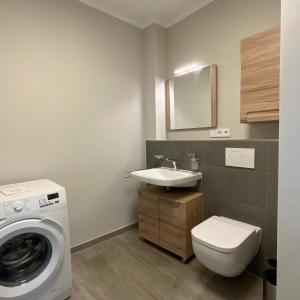 ein Badezimmer mit Waschmaschine und Waschbecken in der Unterkunft Columbus in Petersdorf auf Fehmarn