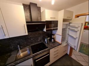 una cucina con armadi bianchi, lavandino e frigorifero di Bunte Kuh a Petersdorf auf Fehmarn