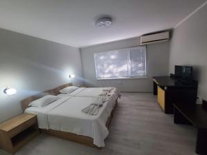 a bedroom with a large white bed and a desk at Комплекс Хиподрума in Dobrich