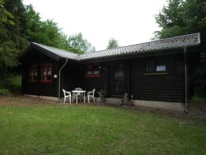 een zwarte hut met een tafel en stoelen in de tuin bij Wunderschönes Ferienhaus Am Waldrand in Bad Arolsen