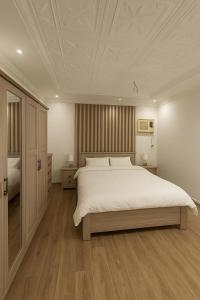 a bedroom with a large white bed and wooden floors at غرفه وصاله بدخول ذاتي in Jeddah