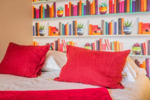 a couch with red pillows in front of a book shelf at L Icone de la Guierle - 1 Chambre in Brive-la-Gaillarde