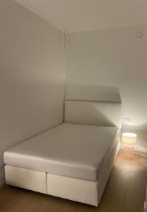 a white bed in a white room with a lamp at Wellness Oase an der Donau in Wien in Vienna