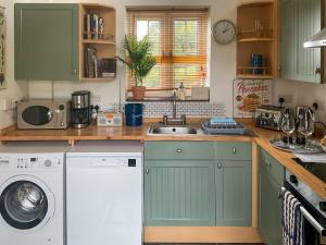 eine Küche mit Spüle und Waschmaschine in der Unterkunft Archers Cottage in Birley