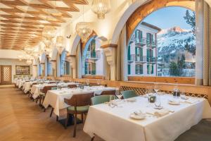 a restaurant with white tables and chairs and a large window at Parkhotel Margna Superior in Sils Maria