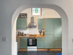 einen Torbogen in einer Küche mit grünen Schränken in der Unterkunft Archers Cottage in Birley