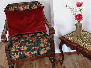 a chair with a pillow and a table with a vase at Ferienwohnung Sauerland Burgfenster in Bilstein