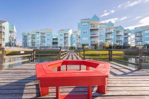 a red bench on a boardwalk in front of condos at Baywatch D11 in Pensacola Beach