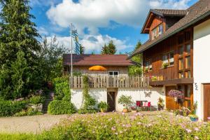 a house with a balcony with an orange umbrella at Ferienwohnung Obstwiese in Hergensweiler