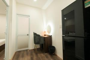 1 dormitorio con TV, silla y espejo en Cashew Inn, en Ho Chi Minh