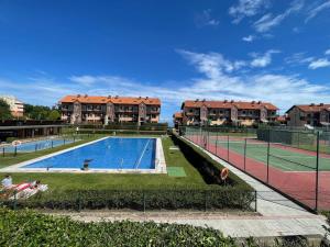 a swimming pool with a tennis court and some buildings at Apartamento Aventuras in Comillas