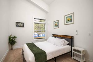 a white bedroom with a bed and a window at Lake & Laughter Unit 2 in Rockaway Beach