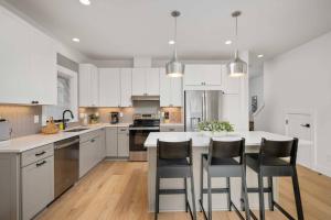 a kitchen with white cabinets and a kitchen island with chairs at Lake & Laughter Unit 1 in Rockaway Beach