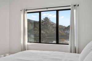 a white bedroom with a large window with a view at Lake & Laughter Unit 1 in Rockaway Beach