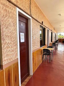 ein Flur mit Tischen und Stühlen und einer braunen Tür in der Unterkunft Golden Sunn Tourist Inn in Puerto Princesa
