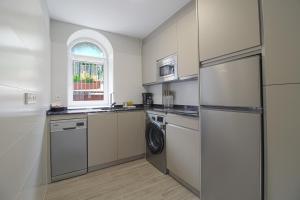 een keuken met een koelkast, een wasmachine en een droger bij Apartamentos Turísticos La Pontificia in Comillas