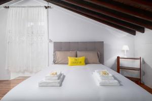 een slaapkamer met een wit bed en een geel kussen bij Casa da Avó in Vila Franca do Campo