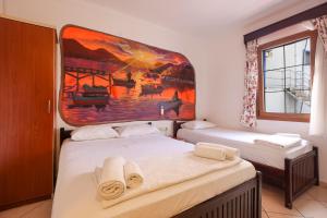 zwei Betten in einem Zimmer mit einem Gemälde an der Wand in der Unterkunft Turunç Pansiyon in Bodrum City