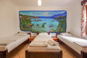zwei Betten in einem Zimmer mit einem Gemälde an der Wand in der Unterkunft Turunç Pansiyon in Bodrum City