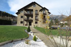 a large stone house with a grass yard at El Molino de Pochas in Bielsa