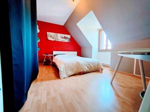 a bedroom with a red wall and a bed at Jean Monnet - Séjour à Auxerre in Saint-Georges-sur-Baulche