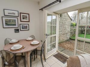 a dining room with a table and chairs and a sliding glass door at Watermill Cottage in Chathill