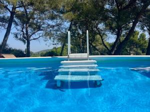 una piscina azul con una silla en el agua en Résidences des Peyrons vue exceptionnelle mer et sur les Iles d'Or, en Carqueiranne