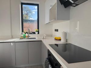eine weiße Küche mit Spüle und Fenster in der Unterkunft Brand New Private House in Croydon in South Norwood + 8 Fotos