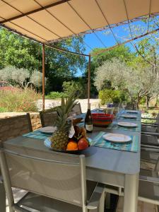 a table with a bowl of fruit and a bottle of wine at Villa spacieuse avec piscine à Saint-Michel-d'Euzet in Saint-Michel-d'Euzet