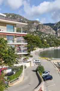 a building with cars parked in a parking lot next to a beach at Appartement exception les pieds dans l'eau in Èze